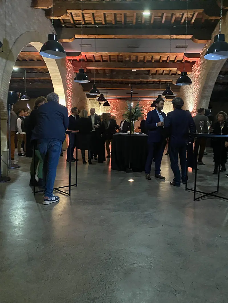 Invités d’un événement d’entreprise au CAPC à Bordeaux pendant un cocktail, éclairage chaleureux et arches en pierre.