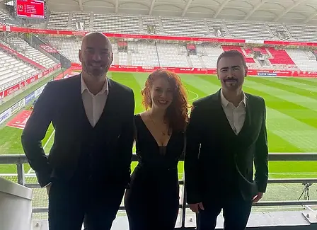 Trio musical (piano, chanteur, bassiste) souriant lors d'une animation musicale au Stade de Reims