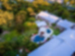 Aerial view of resort roof, pools and lawn area with lots of trees