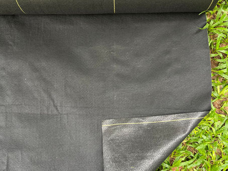 Durable 5 oz Weed Barrier fabric installed in lush vegetation.