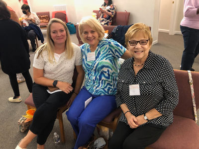 Three women sitting together smiling.