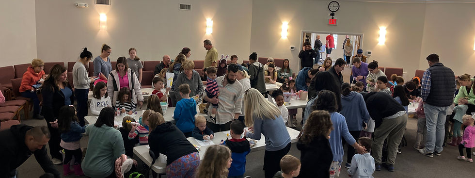 A large group of adults and children doing a craft together at a community event.