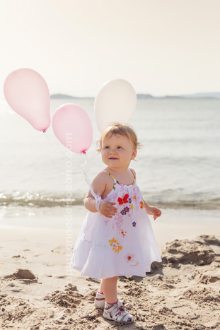 Enfant avec des ballons roses sur une plage à Marseille, coucher de soleil