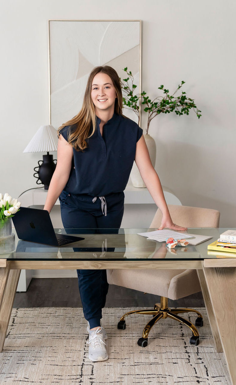 Sophia Apgar standing at a desk wearing grey scrubs
