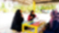 Community members meeting at a colourful beach table to discuss environmental monitoring.j