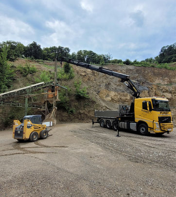Gelber LKW beim Verladen von Maschinen auf einer Baustelle