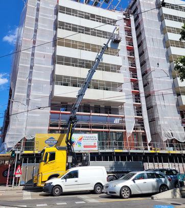 LKW mit ausgefahrenem Kran an Hausfassade