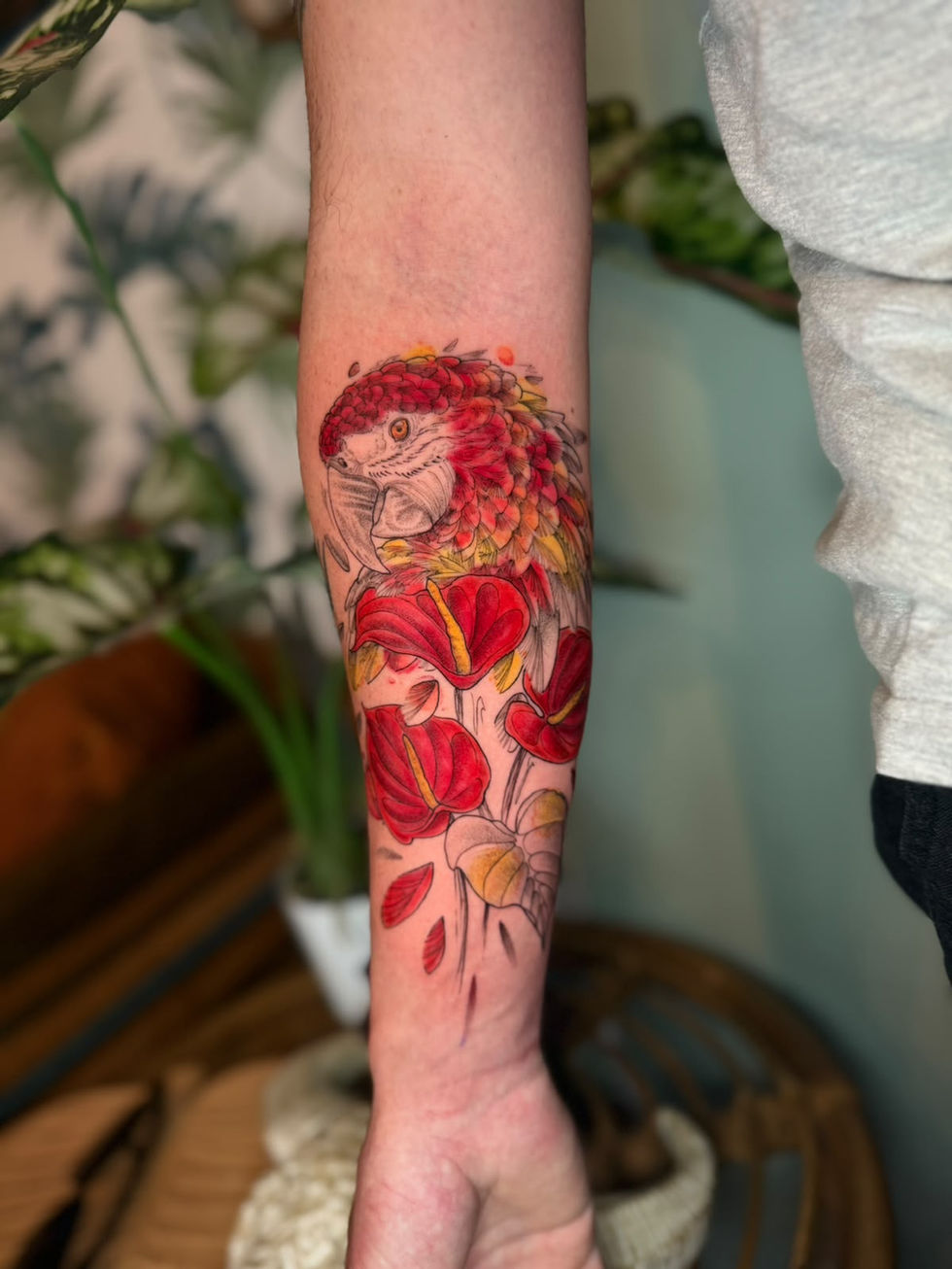 Tatouage floral tropical perroquetréalisé par La Passoire, tatoueuse en Guyane française