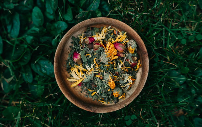 wooden bowl of yoni steaming dried herbs and flowers