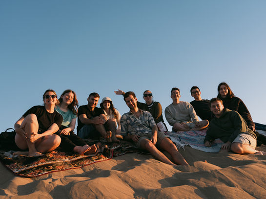 Surf camp guests gathering for a sunset beach picnic in Mirleft, Morocco