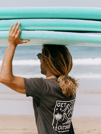 Surfer carrying surfboards on the beach in Mirleft, Morocco