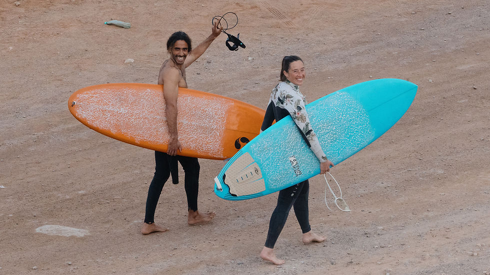 Surfers carrying surfboards while heading to a beginner-friendly surf spot in Morocco.