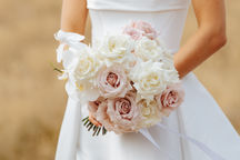 Bride holding a bouquet of white and blush roses.