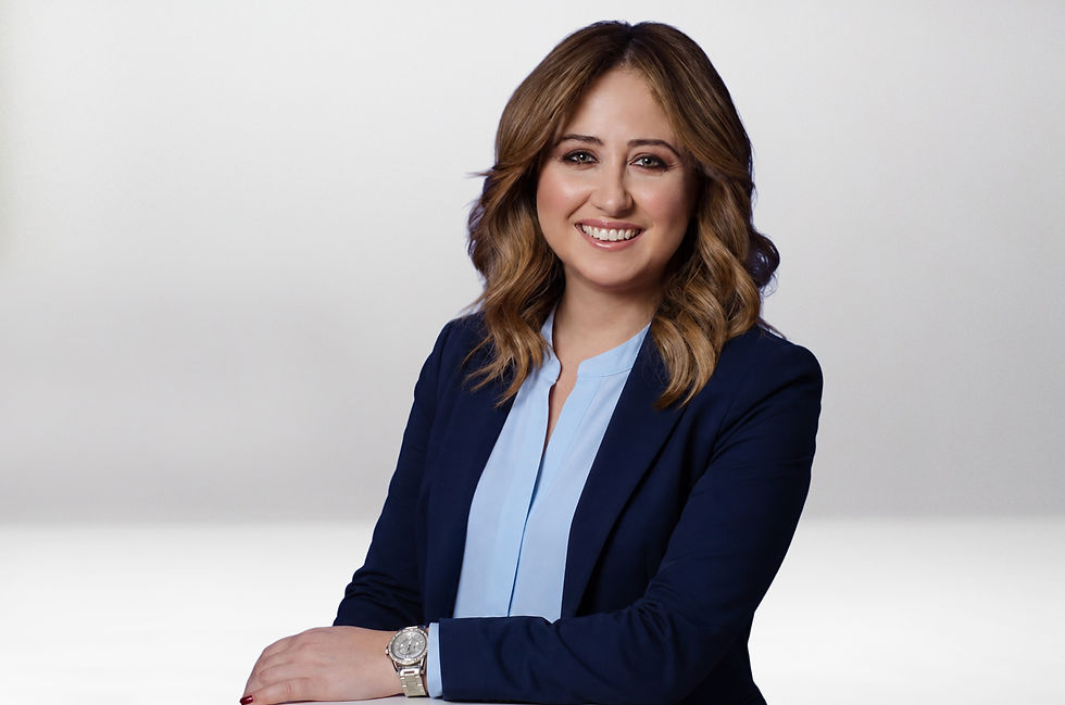Beyaz fonda lacivert ceketli, açık mavi bluzlu gülümseyen kadın; kolları çapraz, profesyonel portre.