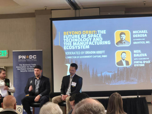 Panelists speak on stage at the PNDC Supply Chain Opportunities Conference, with a presentation screen showing the session on space technology and manufacturing. This image reflects the growing focus on CMMC supplier readiness and cybersecurity expectations across the defense supply chain.