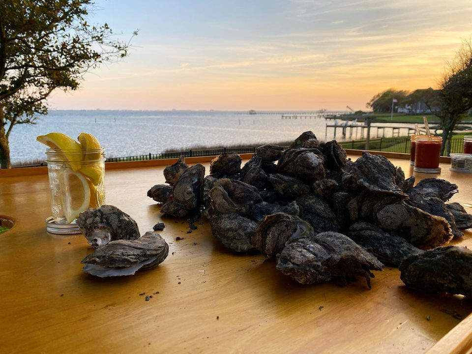 Changing Tide Oyster Company's "South River Salts" (now known as Green Wings) spread out over a wooden oyster roasting table with lemons and their homemade cocktail sauce.