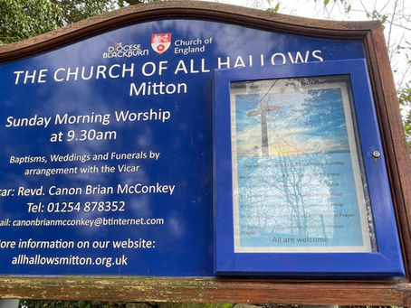 Historic information sign outside All Hallows Church, Great Mitton, seen during a visit exploring medieval church heritage and local history.