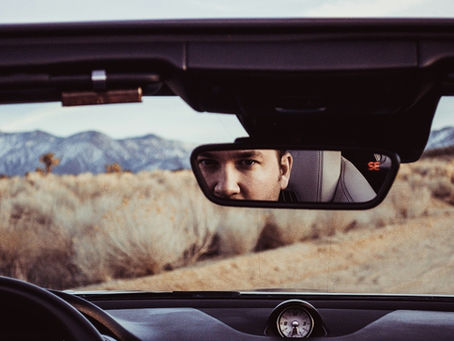 Man looking in car rearview mirror
