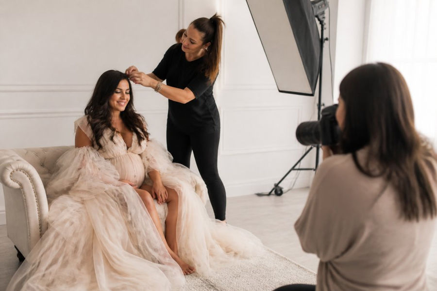Mother in a couture gown getting ready for a luxury family photography session in a bright studio
