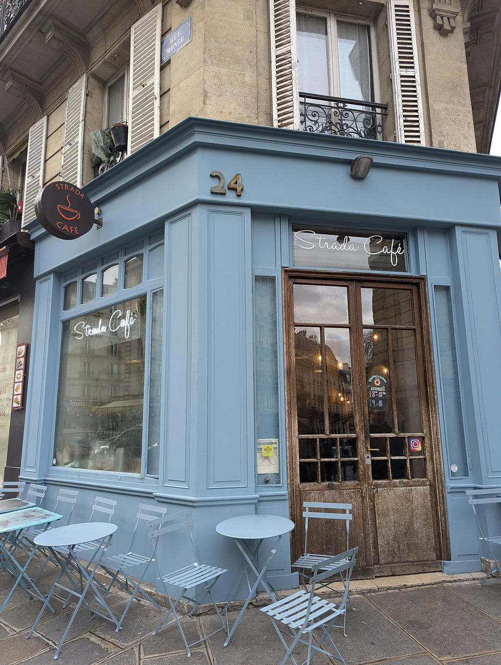 Exterior of a café which is painted blue and bistro tables and chairs outside.