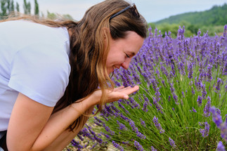 Woman with light brown hair leaning down to smell lavender.
