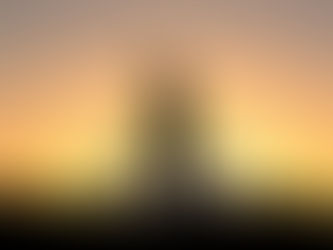 Silhouette of a person with a bike at sunset. They stand on grass, sky glowing with orange and purple hues, creating a calm mood.