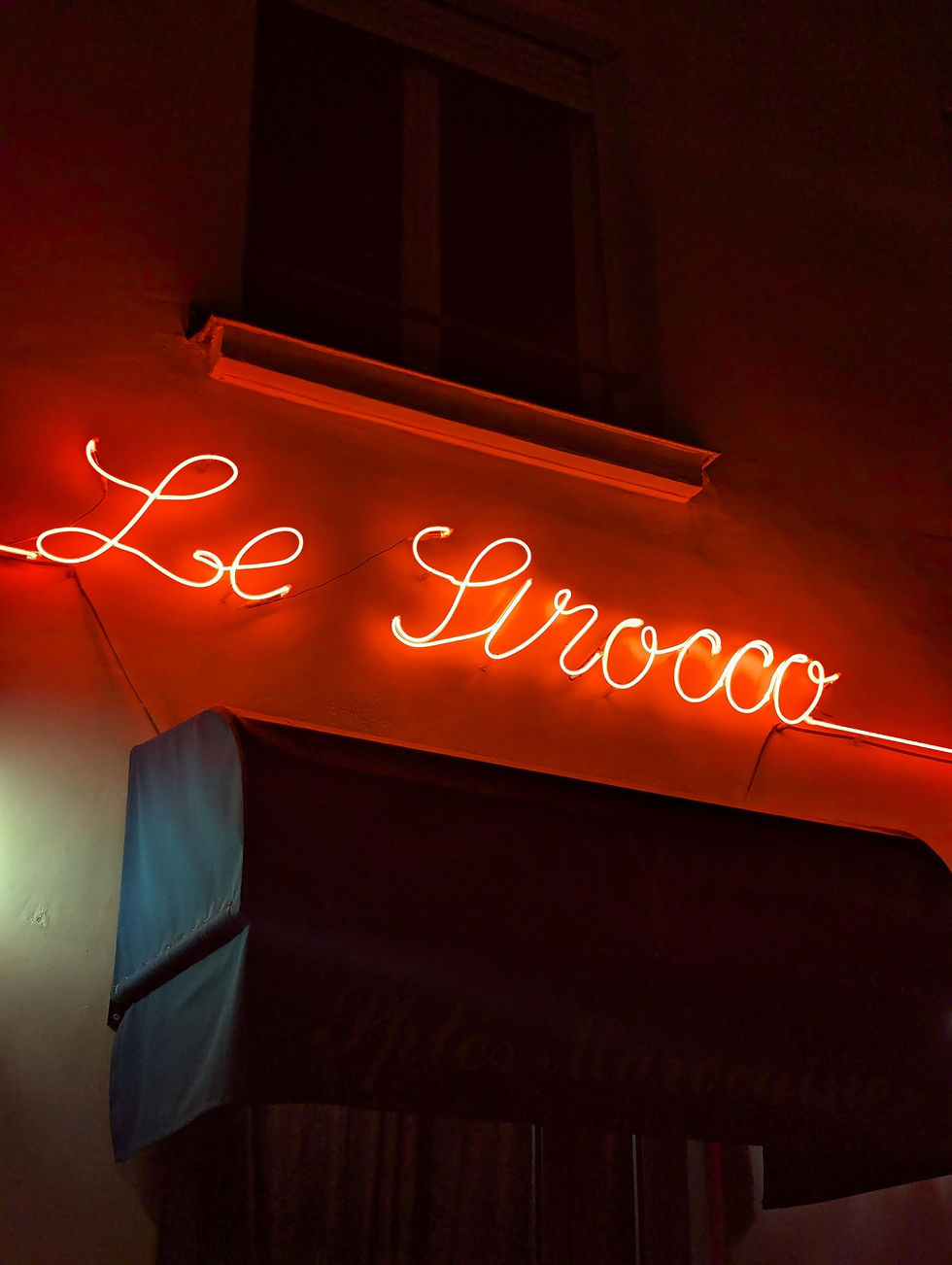 Red neon sign saying Le Sirocco which is a Moroccan restaurant in Paris.