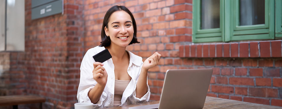 beautiful-young-asian-woman-with-credit-card-sitting-near-laptop-smiling-paying-bills-shop