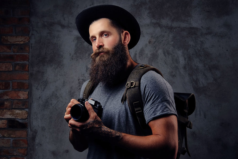 portrait-handsome-bearded-traveler-hat-with-backpack-tattooed-arms-holds-photo-camera-isol