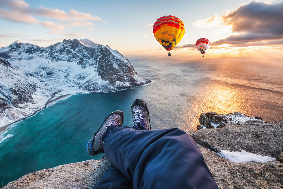 man-hiker-cross-legs-sitting-rock-ridge-with-hot-air-balloon-flying-ocean-sunset.jpg