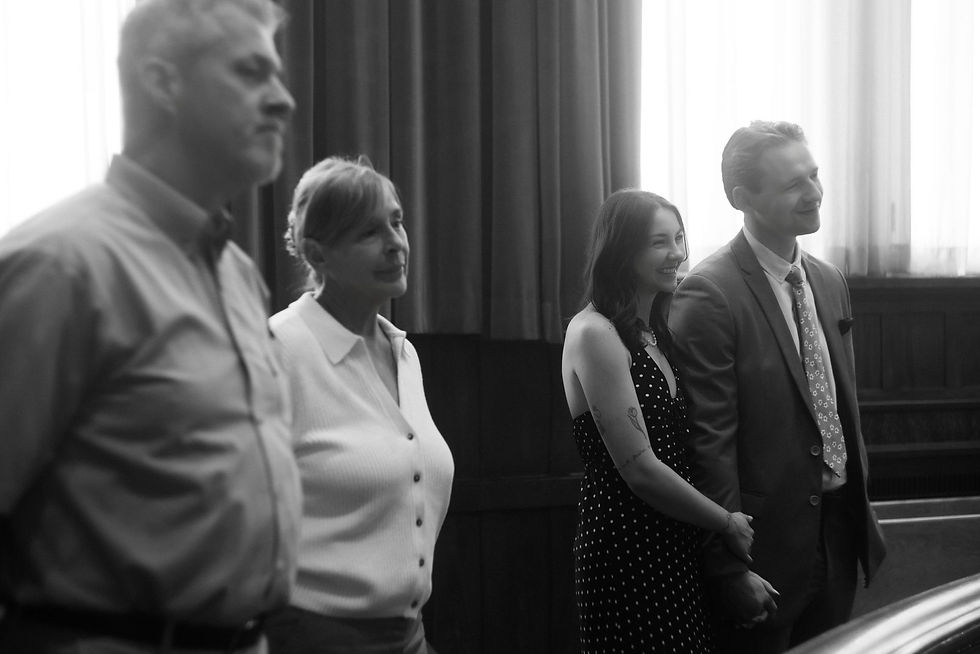 Black and white photograph of four of the people at the wedding, standing together by the windows at Old City Hall.