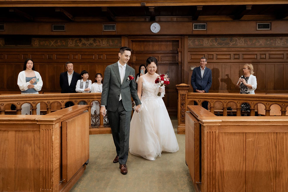 The couple walking between the wooden benches after their ceremony at Old City Hall.