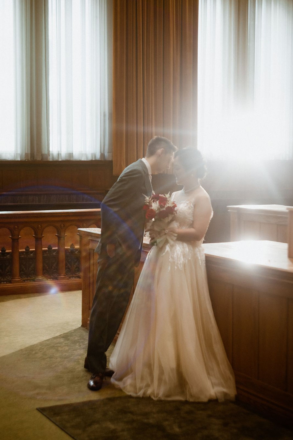 The couple together in the backlight of a tall window inside Old City Hall in Toronto.