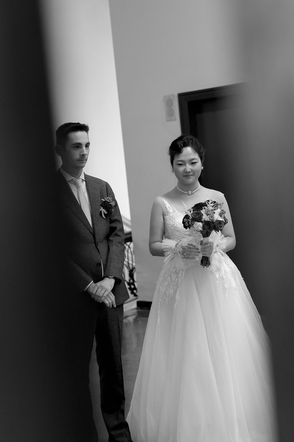 Black and white portrait of the couple by a doorway at Old City Hall in Toronto.