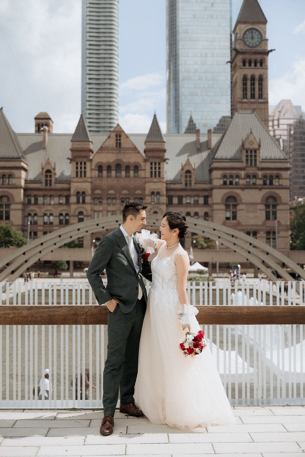 The couple photographed outside in Toronto with the clock tower of Old City Hall behind them and the city beyond.