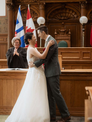 Old City Hall wedding photography in Toronto: the couple at the wooden railing of the former Council Chamber during their civil ceremony.