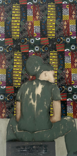 Young man seated in from a stall filled with fabric 