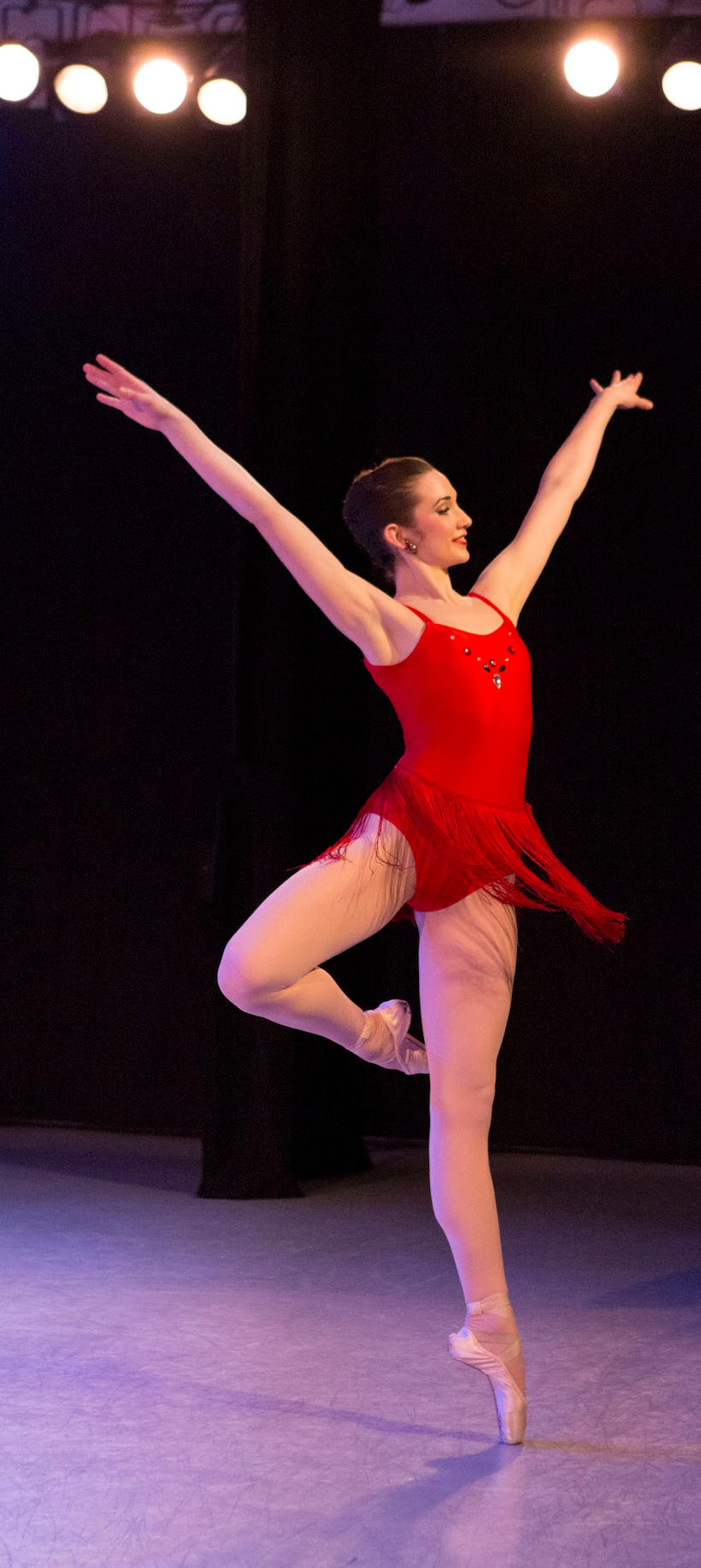 A ballet dancer en pointe wearing a red dress.