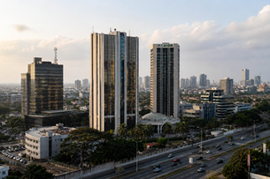 Modern office towers and financial district skyline in an African city, with highways, urban infrastructure, and the African Development Bank headquarters visible in warm daylight.