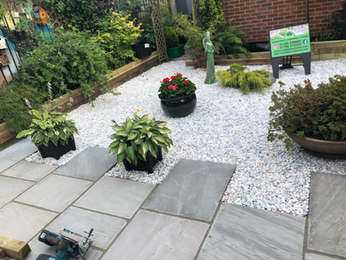 Landscaped garden featuring light gravel, potted flowers, and stone paving.