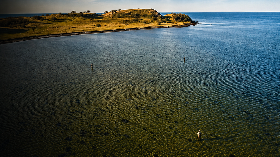 Dronebillede af tre lystfiskere der fisker i en vig ved kysten