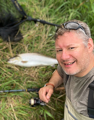 Fiskeguide Lars Nielsen med en stor havørred ved siden af åen