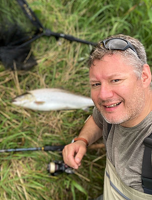 Fiskeguide Lars Nielsen med en stor havørred ved siden af åen.