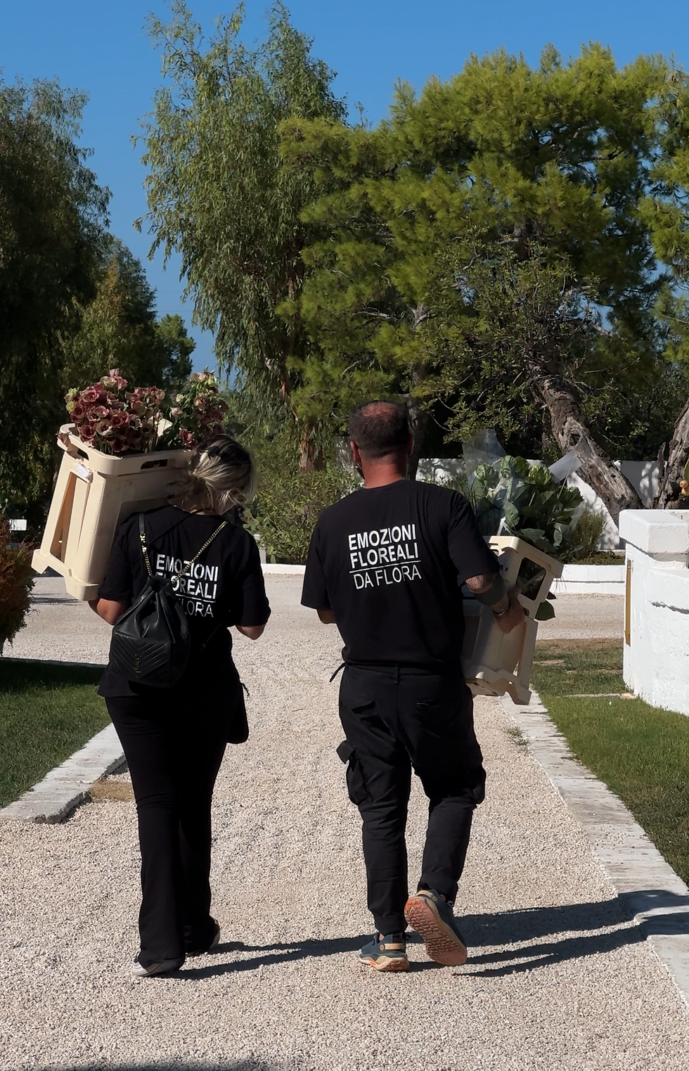 view of two floral designers carrying flowers in a apullian weddign venue