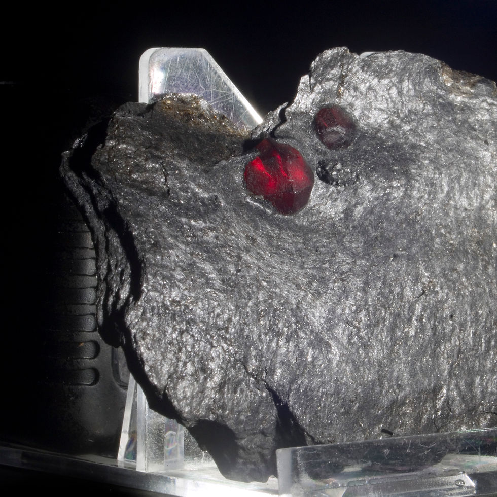 Thumbnail: Three Almandine-Pyrope Garnets in a matrix plate of graphite. Deep red, translucent when backlit and genuinely spectacular, f