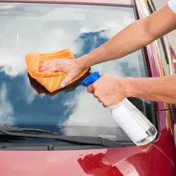 Person-cleaning-cars-windshield-winh-cloth-and-spray.webp