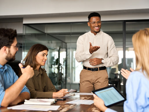 Business team in a modern conference room having a collaborative leadership meeting, with executives discussing strategy around a table with laptops.