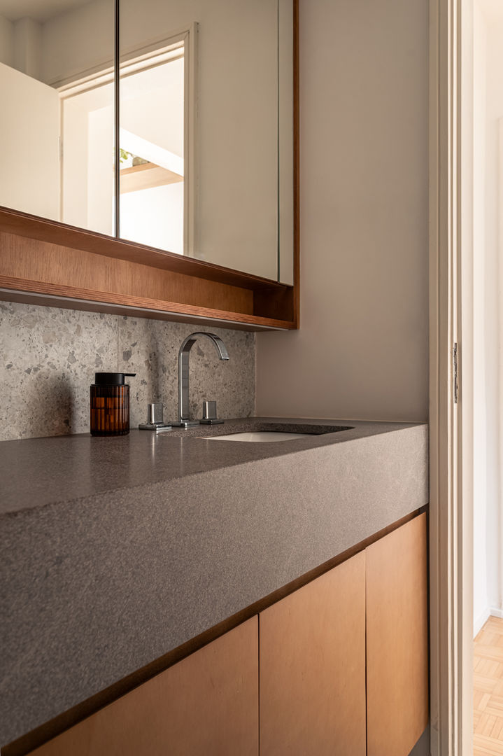 Banheiro contemporâneo com bancada de basalto, porcelanato que imita pedra nas paredes e piso, armários de madeira clara e aéreo com portas espelhadas, combinando elegância e funcionalidade para espaços residenciais modernos.