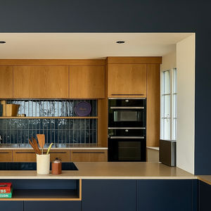 Cuisine ouverte contemporaine avec armoires en bois et bleu marine, un îlot central et une crédence carrelée crédence brillante à l’allure artisanale.