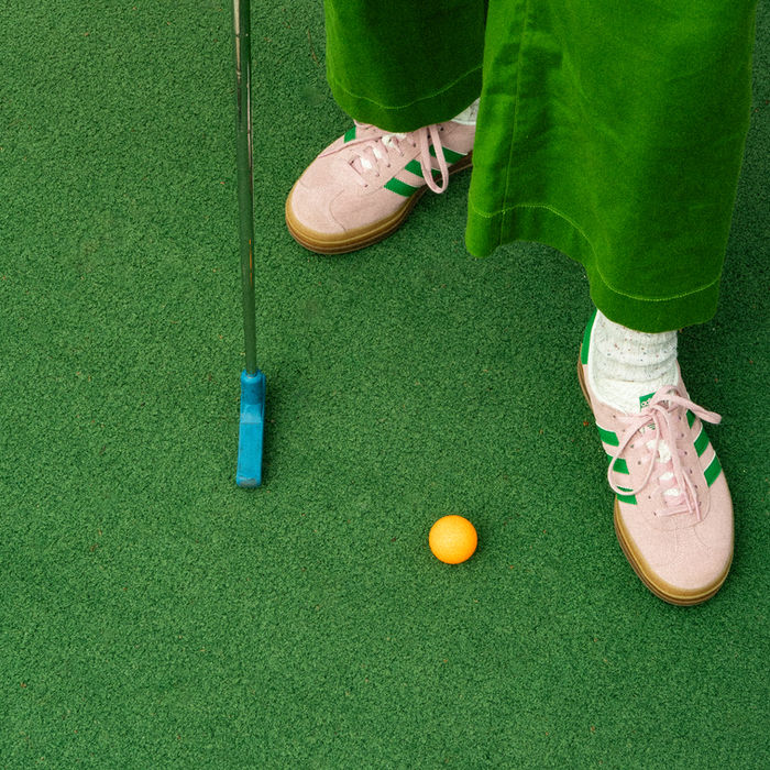 Decorative photo of a mini golf ball and putter on turf